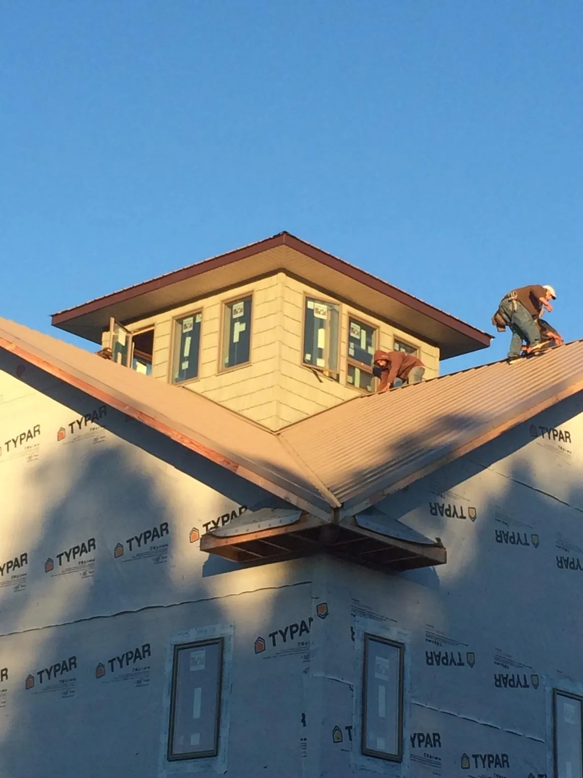 Roofers working around a rooftop cupola on a new metal roof at sunset — Roof Waterproofing in Sea Isle City by Roofing Brothers